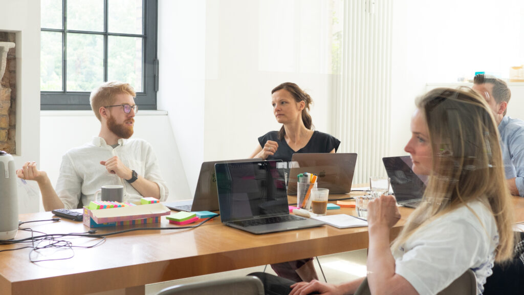 Group of people sitting around an office conference room table in discussion.